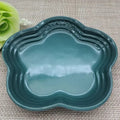 Teal ceramic pet bowl with scalloped edges, ideal for dog or cat food and water, placed on woven mat with green flower accent.